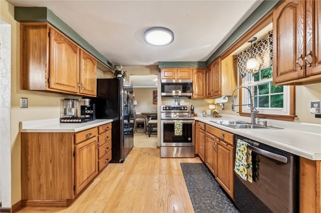 kitchen with appliances with stainless steel finishes, sink, and light wood-type flooring