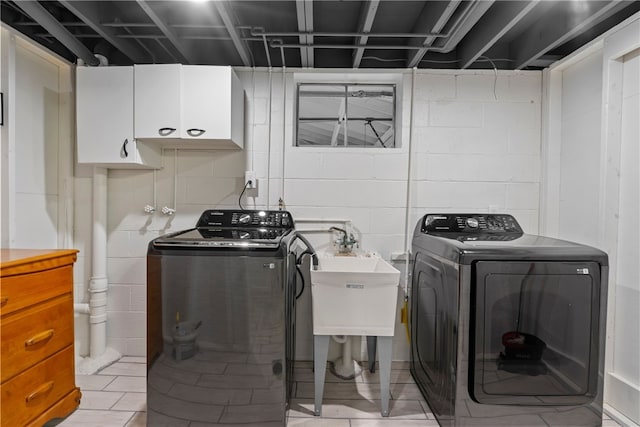 washroom featuring sink, light tile patterned flooring, washing machine and clothes dryer, and cabinets