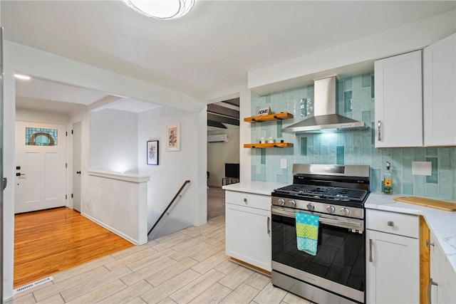3326 New England Rd, West Mifflin, PA 15122 - kitchen with stainless steel gas range oven, wall chimney exhaust hood, light wood-style flooring, decorative backsplash, and white cabinetry