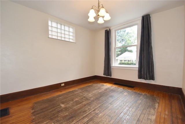 empty room featuring hardwood / wood-style floors and a chandelier