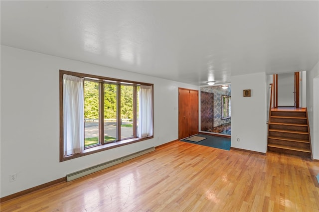 empty room with plenty of natural light, a baseboard heating unit, and light hardwood / wood-style floors