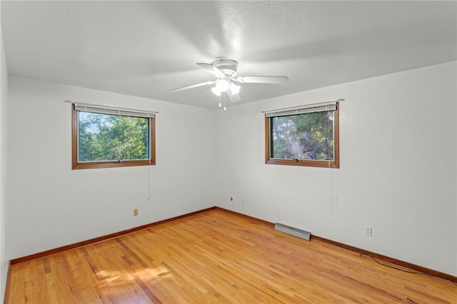 empty room featuring ceiling fan, light wood-type flooring, and baseboard heating