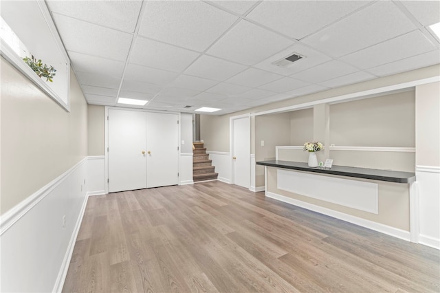 basement with a paneled ceiling and light wood-type flooring