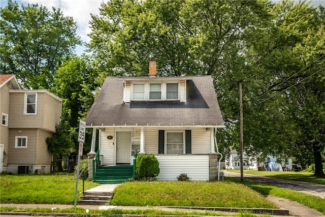 view of front of house with central AC and a front yard