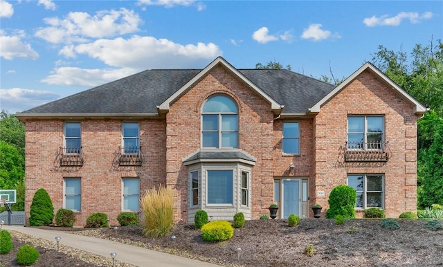 view of front of house featuring brick siding and roof with shingles