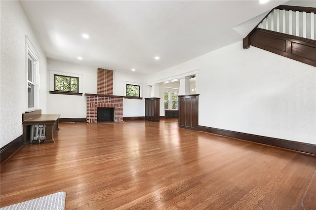 unfurnished living room with a wealth of natural light, a fireplace, baseboards, and wood finished floors