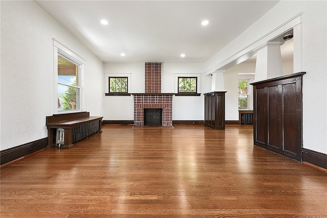 interior space with hardwood / wood-style floors, ornate columns, and a brick fireplace