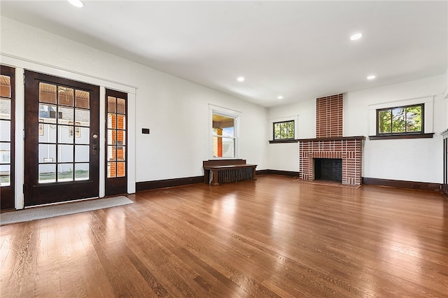 unfurnished living room featuring a brick fireplace, brick wall, and hardwood / wood-style flooring