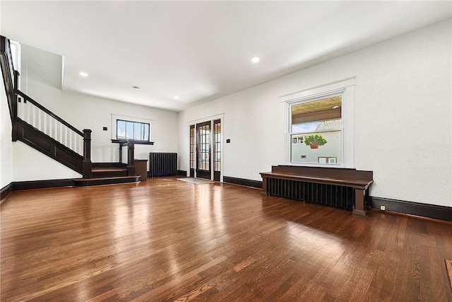 living area with wood finished floors, baseboards, stairs, radiator, and plenty of natural light