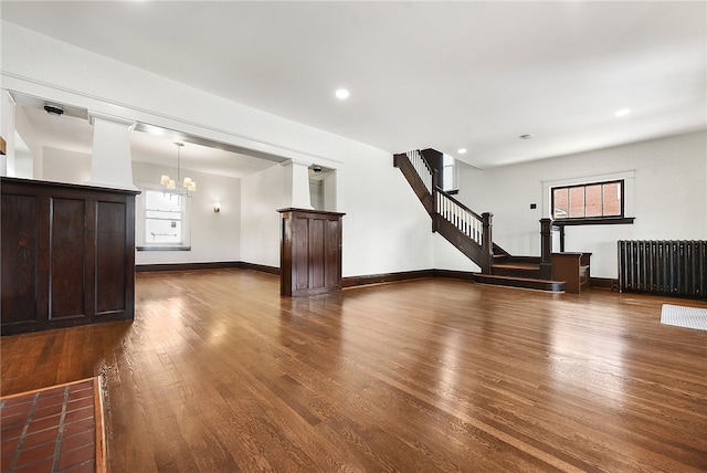 basement with radiator, dark hardwood / wood-style flooring, a chandelier, and a healthy amount of sunlight