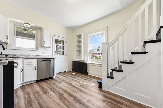 kitchen with decorative backsplash, light hardwood / wood-style flooring, stainless steel dishwasher, and white cabinetry