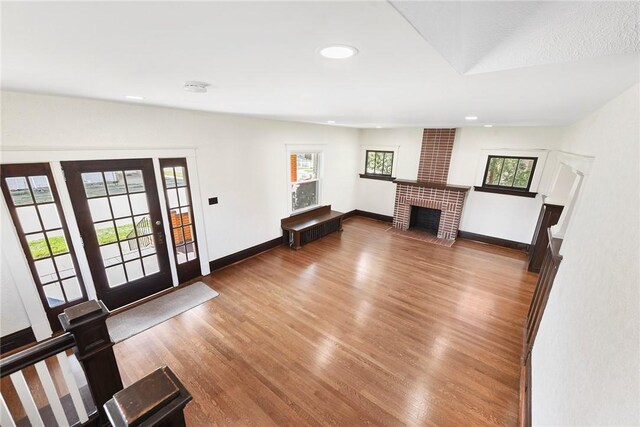 foyer with a brick fireplace, brick wall, hardwood / wood-style flooring, and a healthy amount of sunlight