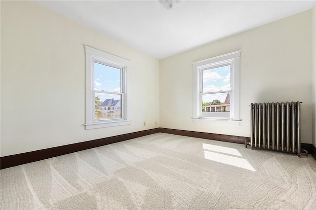 carpeted empty room with baseboards and radiator heating unit