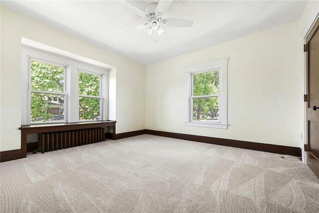 carpeted spare room featuring ceiling fan and radiator