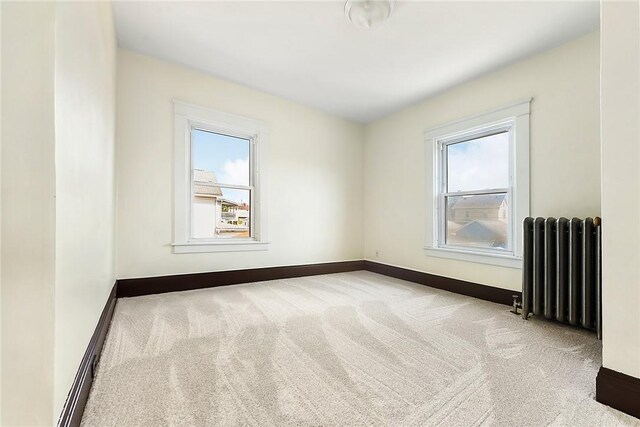 carpeted spare room with radiator heating unit and a healthy amount of sunlight