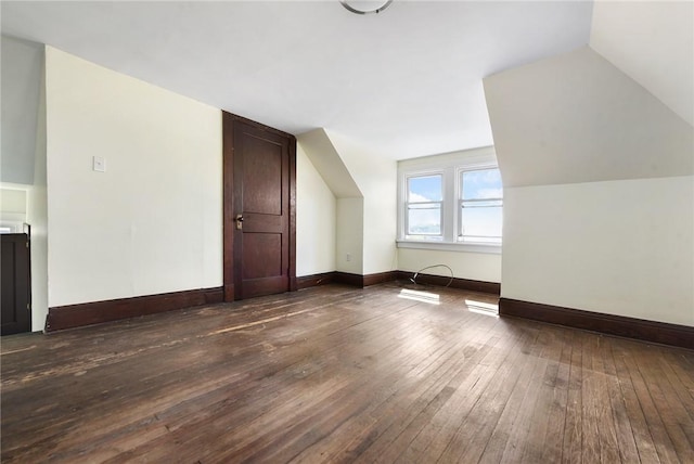 additional living space featuring dark wood-style flooring, vaulted ceiling, and baseboards