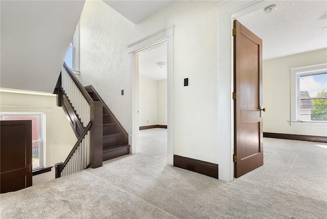 interior space featuring stairs, baseboards, and light colored carpet