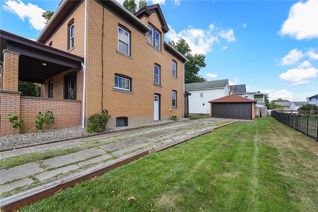 exterior space featuring a garage, a lawn, and an outbuilding