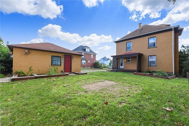 rear view of house featuring brick siding, a lawn, and fence