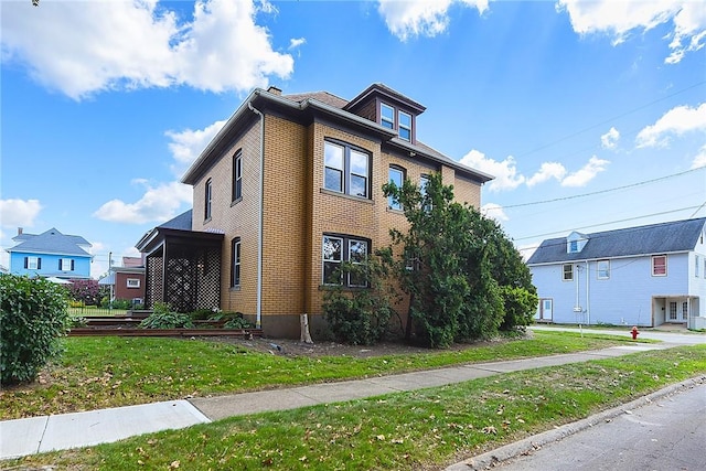 american foursquare style home with a front lawn and brick siding