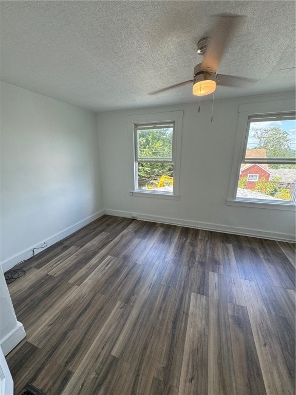 empty room featuring ceiling fan, a textured ceiling, plenty of natural light, and dark hardwood / wood-style floors