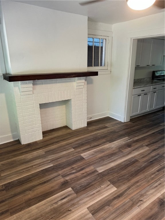 unfurnished living room with dark hardwood / wood-style floors and a brick fireplace