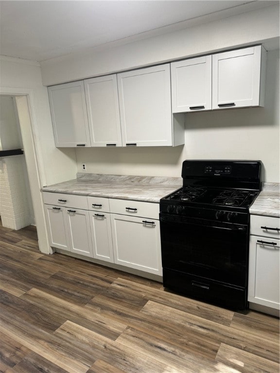 kitchen featuring gas stove, ornamental molding, white cabinetry, and dark hardwood / wood-style floors