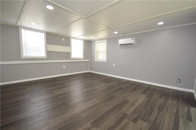 basement with recessed lighting, dark wood-style flooring, a wall unit AC, and baseboards