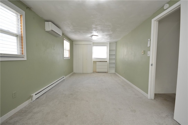 spare room featuring a baseboard heating unit, a wall unit AC, light colored carpet, and a wealth of natural light