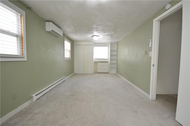 empty room with light colored carpet, baseboards, a wall unit AC, and baseboard heating