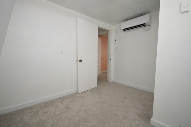 spare room featuring light carpet, a wall mounted AC, and baseboards