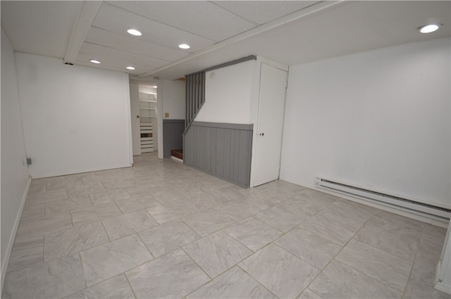 basement with light tile patterned floors, a drop ceiling, and a baseboard radiator