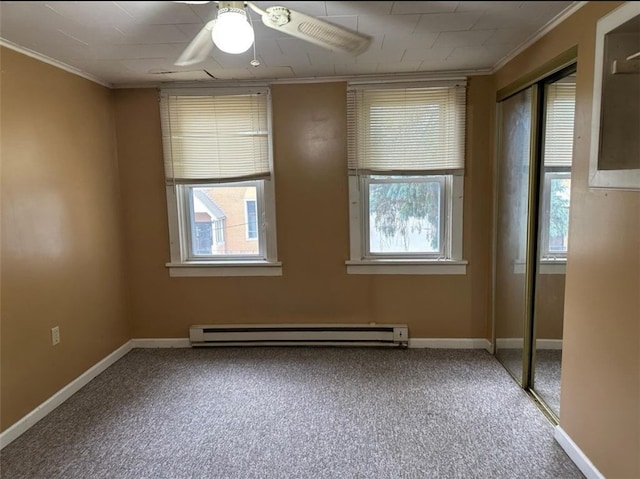 carpeted empty room with crown molding, a wealth of natural light, ceiling fan, and a baseboard radiator