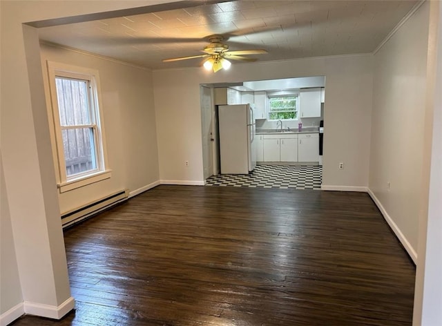 spare room with dark wood-type flooring, ceiling fan, a baseboard radiator, ornamental molding, and sink