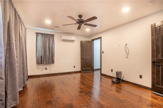 spare room with hardwood / wood-style floors, a wall mounted AC, and ceiling fan