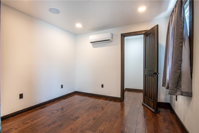 unfurnished room with dark wood-type flooring and an AC wall unit