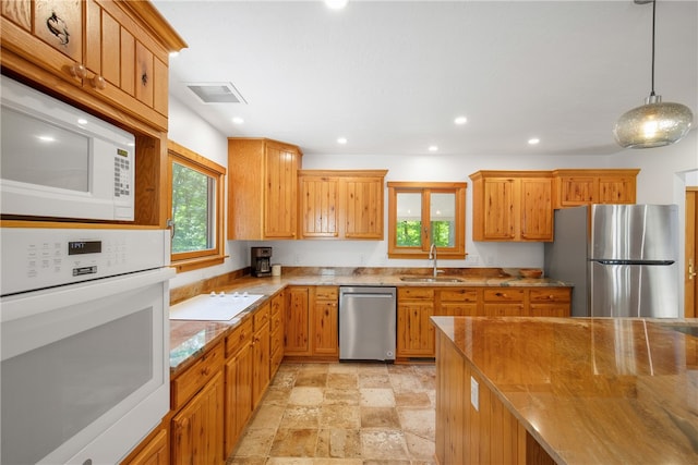 kitchen with appliances with stainless steel finishes, light tile patterned floors, sink, and pendant lighting