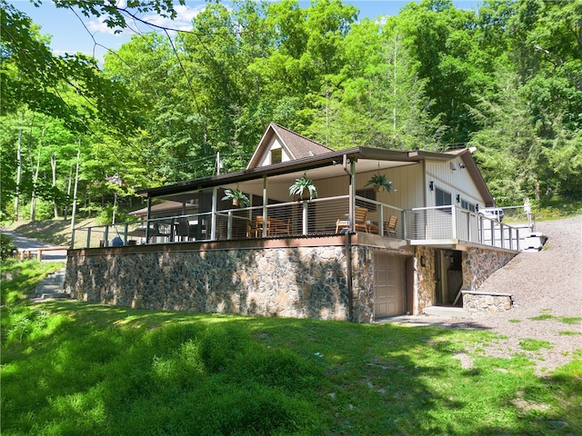 rear view of property featuring a yard, a garage, and a deck