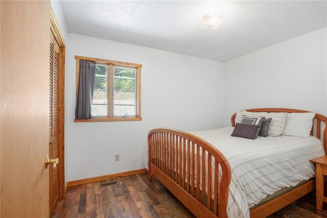 bedroom with dark hardwood / wood-style flooring and a closet