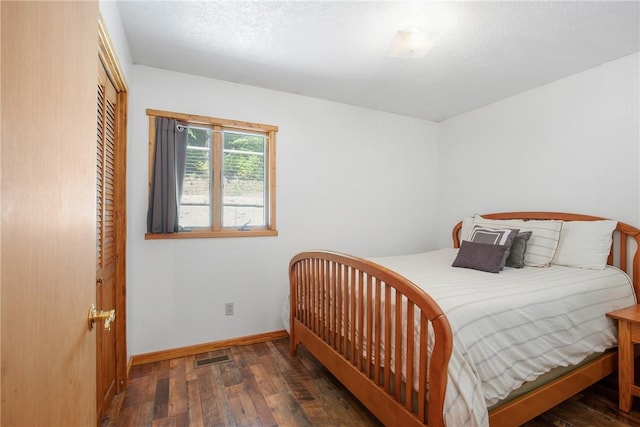 bedroom featuring dark wood-style floors, a closet, visible vents, a textured ceiling, and baseboards