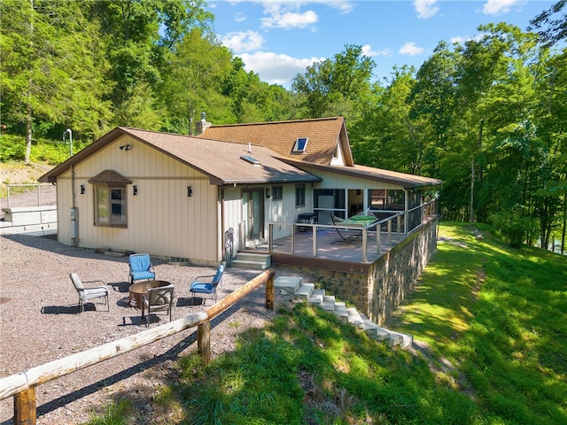 back of house featuring a lawn, a deck, an outdoor fire pit, and a patio area