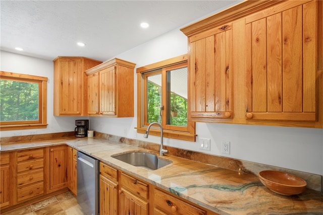 kitchen featuring light stone counters, sink, light tile patterned flooring, and dishwasher