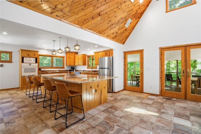 kitchen featuring white appliances, wood ceiling, hanging light fixtures, high vaulted ceiling, and a kitchen island