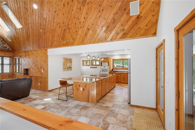 kitchen featuring a skylight, light tile patterned floors, high vaulted ceiling, a kitchen breakfast bar, and a center island