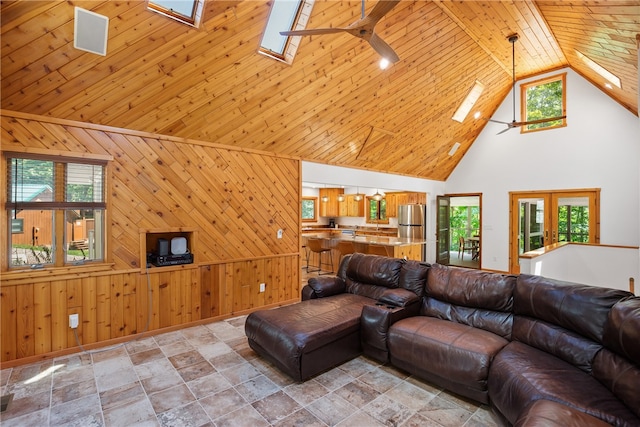 living room with wood ceiling, a wealth of natural light, a skylight, light tile patterned flooring, and high vaulted ceiling