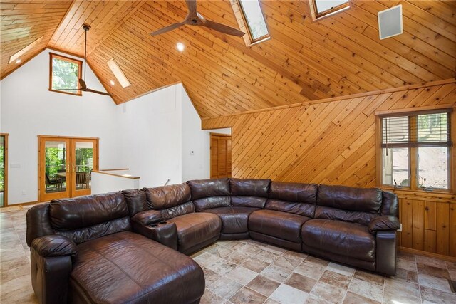 living room with a skylight, light tile patterned floors, high vaulted ceiling, french doors, and wooden ceiling