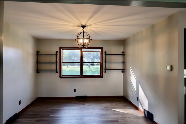 unfurnished room featuring dark wood-type flooring and a notable chandelier