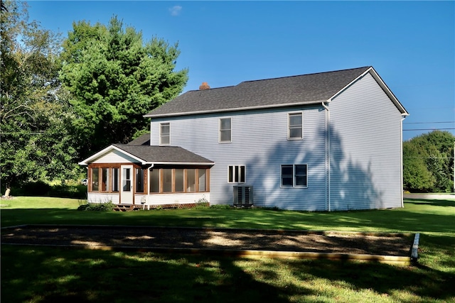 rear view of house with central air condition unit, a lawn, and a sunroom