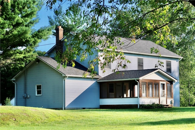 rear view of property with a yard and a sunroom