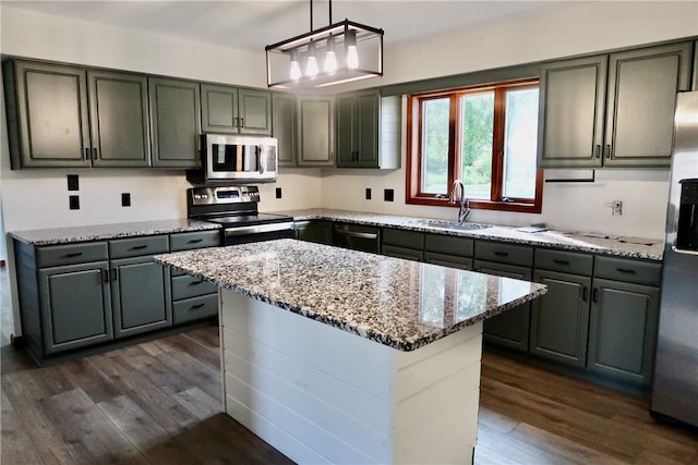 kitchen featuring dark hardwood / wood-style floors, hanging light fixtures, stainless steel appliances, sink, and a center island